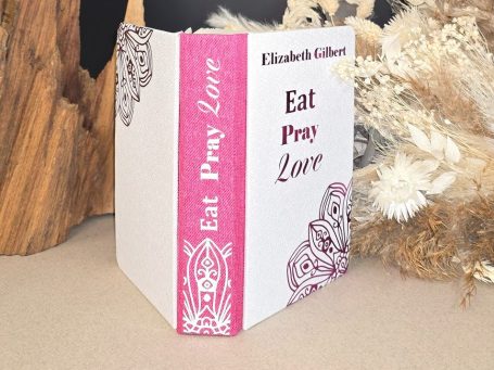 Buchcover von "Eat Pray Love" mit buntem Rand und floralem Design.
