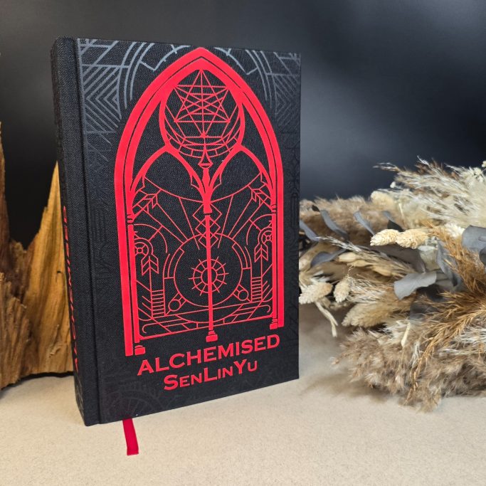 Schwarzes Notizbuch mit rotem, geometrischen Design und dem Titel "ALCHEMISED".