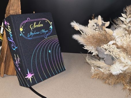 Seelen - Stephenie Meyer Schwarzes Buch mit bunten, glitzernden Schriftzug und dekorativen Elementen.