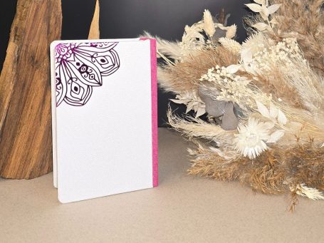 Eat Pray Love – Elizabeth Gilbert
Buch mit floralem Muster und pinkem Rand, umgeben von trockenen Pflanzen.