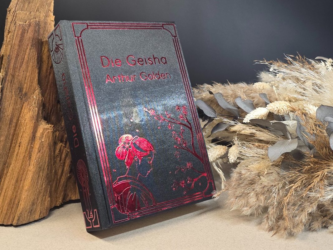 Ein Buch mit roten Verzierungen und einer blühenden Pflanze auf dem Einband.