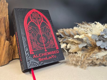 Alchemised - SenLinYu  Schwarzes Buch mit rotem Schriftzug "ALCHEMISED SenLinYu" und dekorativem Muster.