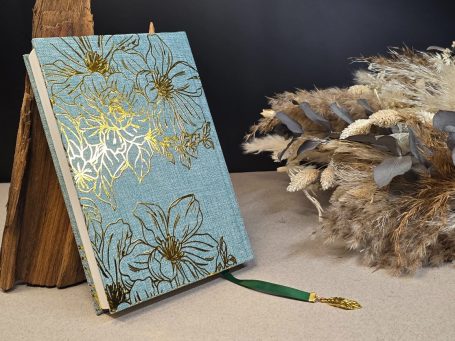 Das Parfum - Patrick Süskind
Buch mit goldenen Blumenmustern und grünem Lesezeichen, neben dekorativen Ästen.