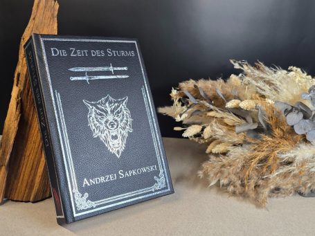 The Witcher - Kurzgeschichten - Andrzej Sapkowski&nbsp; Ein Buch mit dem Titel „Die Zeit des Sturms“ und dekorativen Pflanzen im Hintergrund.