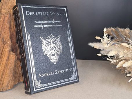 Schwarzes Buch "Der letzte Wunsch" von Andrzej Sapkowski, auf einem Tisch mit Deko.