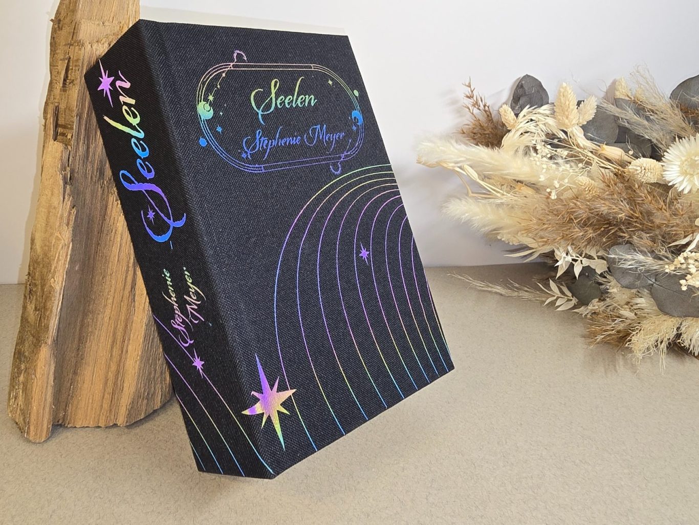 Seelen - Stephenie Meyer Schwarzes Buch mit bunten, glitzernden Schriftzügen und bunten Designlinien.