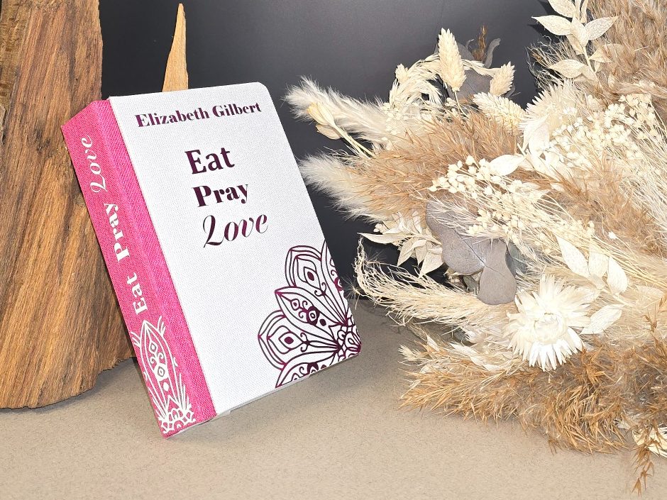 Eat Pray Love – Elizabeth Gilbert Buchcover von "Eat Pray Love" mit dekorativen Trockenblumen im Hintergrund.