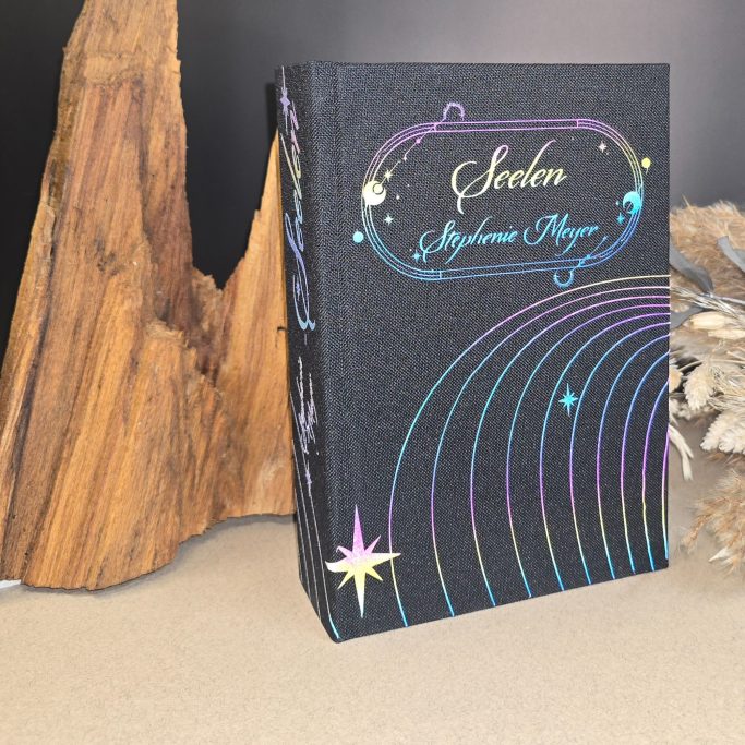 Schwarzes Buch mit bunten, glitzernden Schriftzügen und geschwungenem Design.