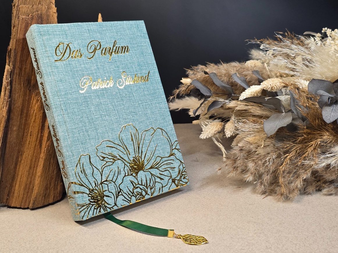 Das Parfum - Patrick Süskind
Buch das Parfum, blaugrüner Einband, goldenen Akzenten und einem grünen Lesezeichen.