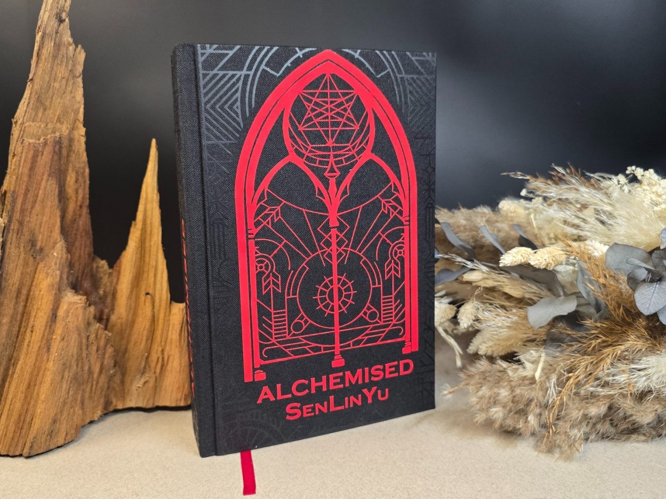 Alchemised - SenLinYu Schwarzes Buch mit rotem Alchemie-Design und gleichfarbigem Titel.