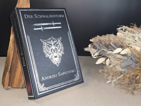 The Witcher - Pentalogie - Andrezj Sapkowski Ein Buch mit dem Titel „Der Schwalbenturm“ und einem Wolf-Emblem auf schwarzem Cover.