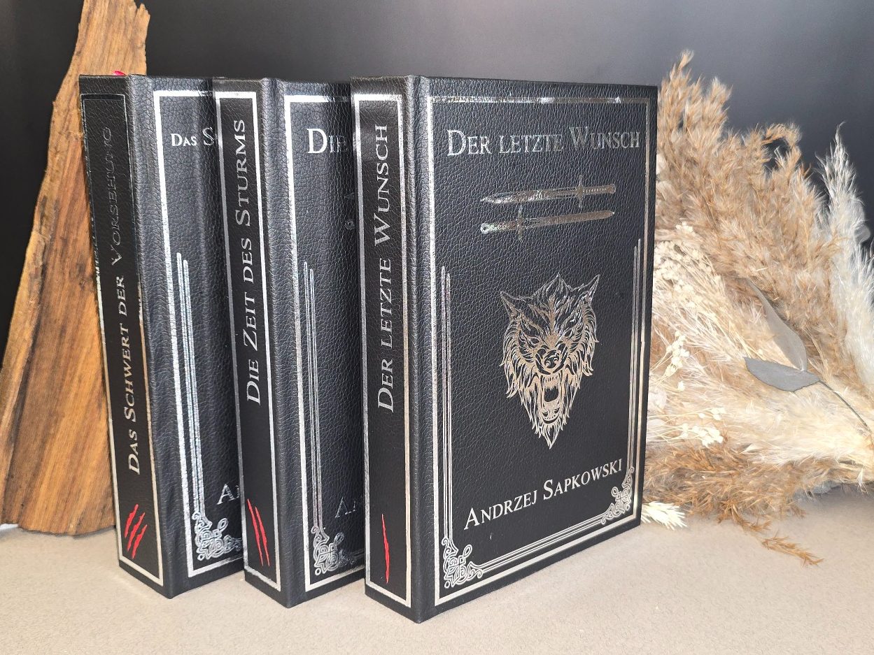 The Witcher - Kurzgeschichten - Andrzej Sapkowski&nbsp; Drei schwarze Bücher mit wolfartigem Coverdesign auf einem neutralen Untergrund.