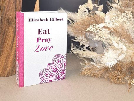 Buch "Eat Pray Love" von Elizabeth Gilbert mit dekorativem Hintergrund.